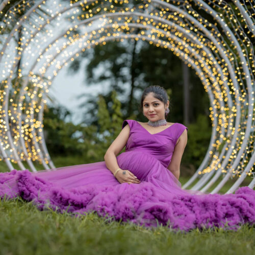 Maternity photoshoot of women sitting in lawn light behind