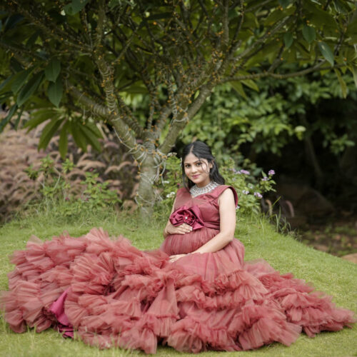 Maternity photoshoot of women sitting in lawn wearing gown